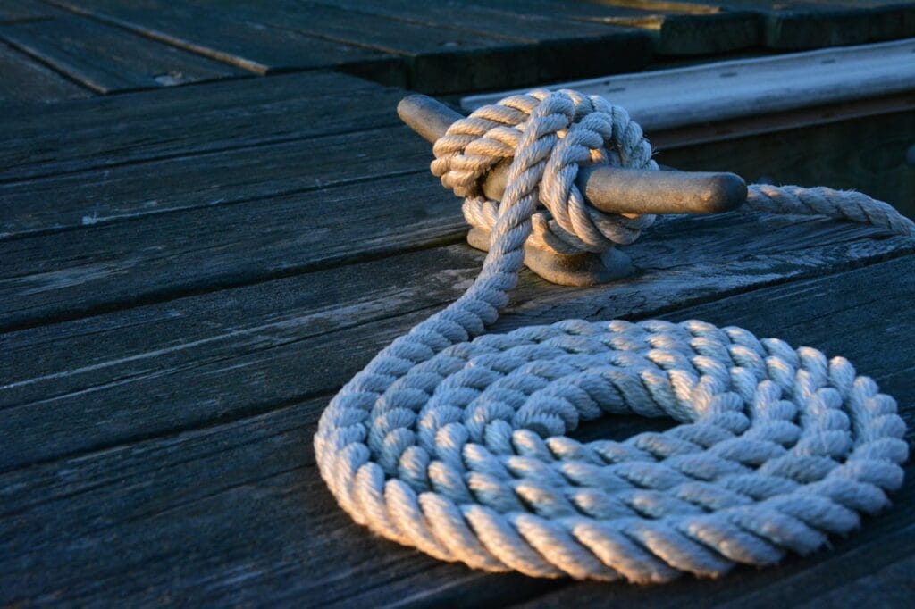 pexels-photo-275637 Close-up of a sturdy nautical knot on a weathered wooden dock at sunset.